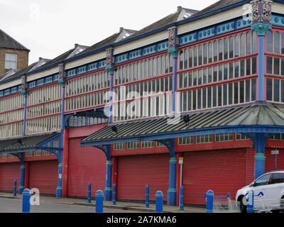 Le hall et coloré de la marché Huddersfield peints en rouge bleu et blanc avec de nombreuses fenêtres et portes fermées de l'obturateur Yorkshire Angleterre Banque D'Images