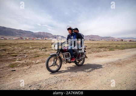 La Mongolie 2019-05-04 hommes mongole Ulgii ride moto à champ sur fond de steppe village ang vous saluent. Asiatique authentique Concept Banque D'Images