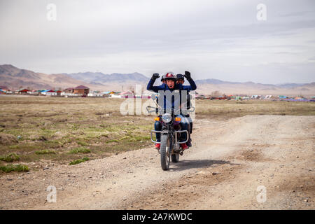 La Mongolie 2019-05-04 hommes mongole Ulgii ride moto à champ sur fond de steppe village ang vous saluent. Asiatique authentique Concept Banque D'Images