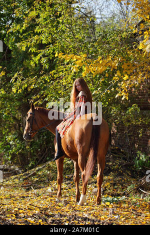 Beautiful country girl bareback monter son cheval en automne route de campagne au coucher du soleil Banque D'Images