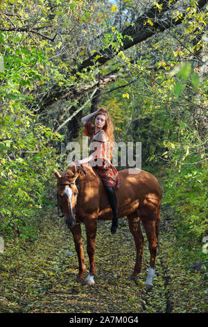 Beautiful country girl bareback monter son cheval en automne route de campagne au coucher du soleil Banque D'Images