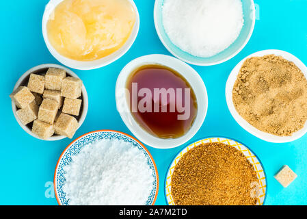 Différents types de Sucre et édulcorants dans les bols, tels que noix de coco, canne à sucre pur, le glaçage, le sirop d'érable, sucre mou brun foncé, miel, cubes démérara Banque D'Images