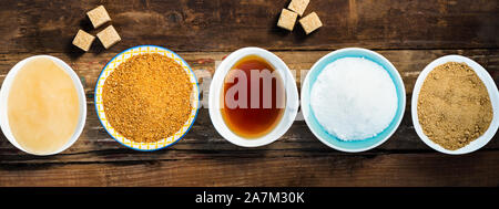 Différents types de Sucre et édulcorants dans les bols, tels que noix de coco, canne à sucre pur, le glaçage, le sirop d'érable, sucre mou brun foncé, miel, cubes démérara Banque D'Images