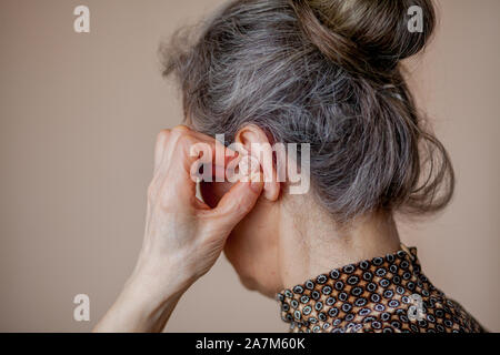 Libre senior woman insertion de prothèse dans ses oreilles. Banque D'Images