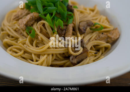 Spaghetti crémeux au poulet et champignons mixtes. Parsemé d'oignons de printemps coupés en rondelles. Fraîchement préparés et servis comme un repas rapide et sain Banque D'Images