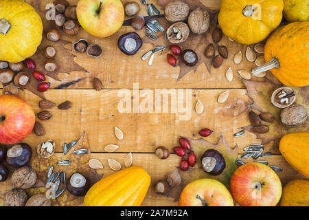 Cadre d'automne avec des fruits, les citrouilles et les écrous sur fond de bois rustique, vue du dessus avec l'exemplaire de l'espace. Concept d'automne arrière-plan. Banque D'Images