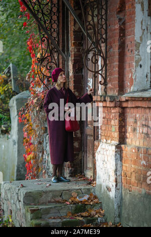 Une femme avec une lettre frappe à la porte d'une maison ancienne. Banque D'Images