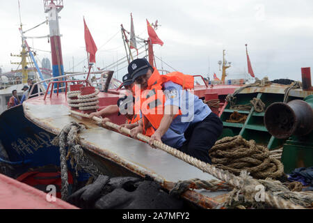 Aider les policiers les pêcheurs locaux à renforcer les bateaux de pêche et se préparer au prochain Typhon Mitag à Hefei City, Zhejiang Province de Chine orientale Banque D'Images