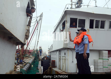 Aider les policiers les pêcheurs locaux à renforcer les bateaux de pêche et se préparer au prochain Typhon Mitag à Hefei City, Zhejiang Province de Chine orientale Banque D'Images