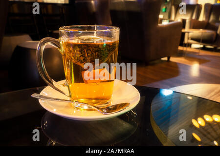 La tisane infuser dans une tasse en verre sur une table en verre de nuit avec copie espace. Banque D'Images