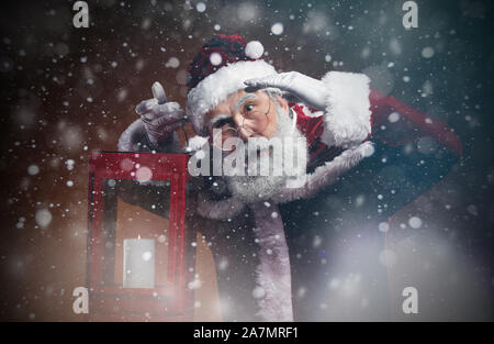 Taille portrait de fairytale Santa holding lantern marche à travers une tempête de neige dans la nuit, copy space Banque D'Images