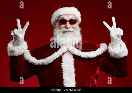Taille portrait de funky Santa portant des lunettes de soleil et smiling at camera prêt à profiter de Noël partie Banque D'Images