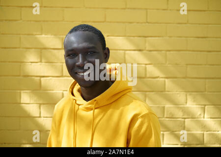 Jeune homme africain souriant de mur jaune en arrière-plan Banque D'Images