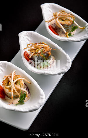 Rouleaux de filet de bar cuit au four farcies aux légumes et sauce aux champignons, sur un fond sombre, l'espace de copie. Banque D'Images