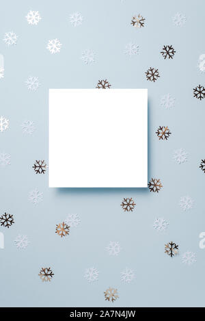 Papier blanc décoré avec des flocons de neige carte sur fond bleu. Nouvelle année, Noël et le concept d'hiver. Mise à plat, vue du dessus, copy space Banque D'Images