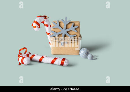 Boîte cadeau de Noël avec de l'emballage, décoré avec des étoiles de neige et de noël ornement canne sur fond de couleur pastel. Vue avant Banque D'Images