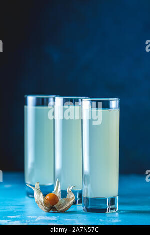Cocktail sans alcool avec l'Ouzo anis grec brandy ou de boire de l'alcool en arabe dans grand verre de Raki, décorées Physalis peruviana et le sucre brun sur bleu c Banque D'Images