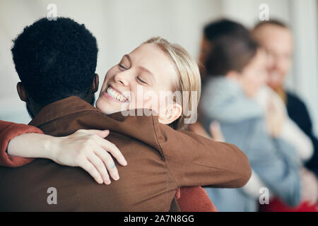 Portrait of smiling young woman hugging ami afro-américain tout en se félicitant de l'autre partie, à l'espace de copie Banque D'Images