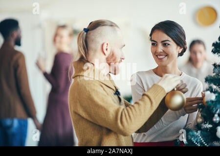 Taille portrait de couple moderne hanging ornaments on Christmas Tree pendant party banquet, copy space Banque D'Images