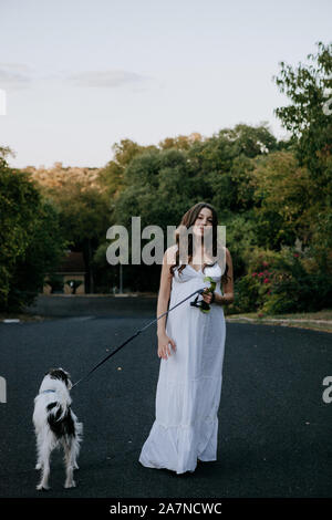 Femme enceinte robe blanche promener son chien Banque D'Images