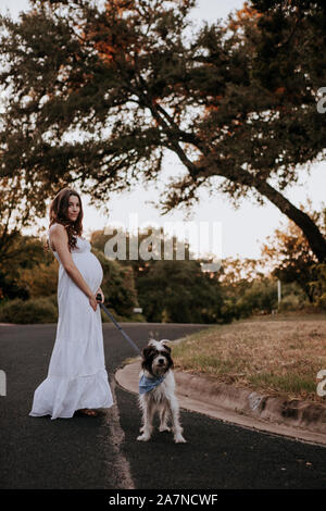 Femme enceinte robe blanche promener son chien Banque D'Images
