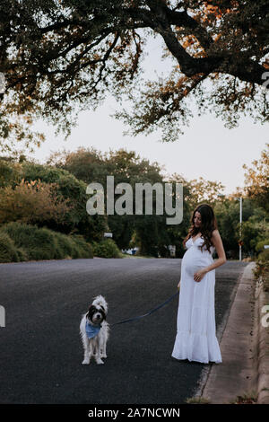 Femme enceinte robe blanche promener son chien Banque D'Images