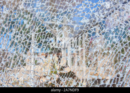 Surface de verre cassée avec jardin contexte en bas. Double couche, surface en verre de sécurité trempé avec de petits morceaux de verre visible Banque D'Images