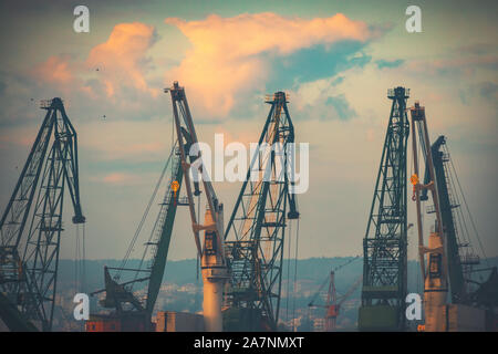 Coucher de soleil sur des grues industrielles à port de mer commercial de la ville de Varna, Bulgarie libre Banque D'Images