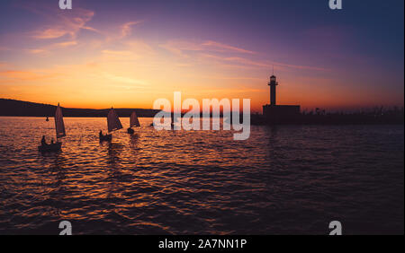 Vent Voile Bateaux au coucher du soleil près de Lighthouse et port mer Varna, Bulgarie. Le sport de la concurrence. Banque D'Images