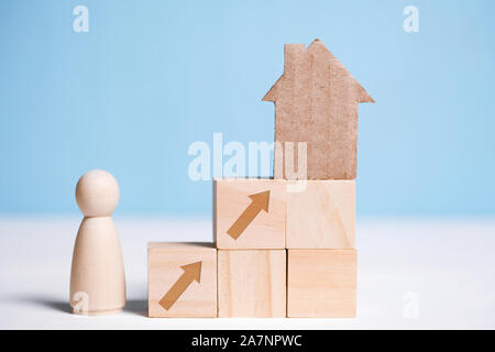 Abstract maison en carton sur des cubes en bois et l'homme. Le concept de l'achat d'une maison comme un objectif. Close up. Banque D'Images