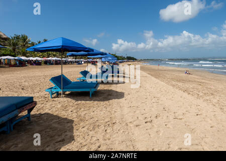 Une rangée de chaises longues et parasols vides attendent les touristes sur la plage de Kuta Bali, Indonésie Banque D'Images