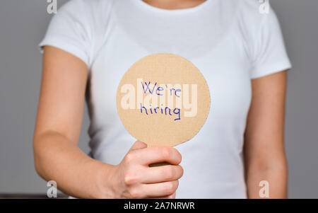 Les jeunes femmes montrant carton rond papier avec texte manuscrit - Nous recrutons, . Banque D'Images