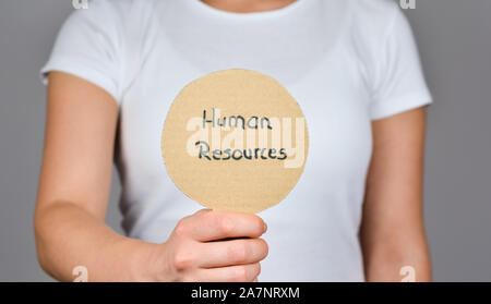 Les jeunes femmes montrant carton rond papier avec texte manuscrit - Ressources Humaines, . Banque D'Images