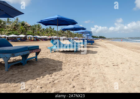 Une rangée de chaises longues et parasols vides attendent les touristes sur la plage de Kuta Bali, Indonésie Banque D'Images
