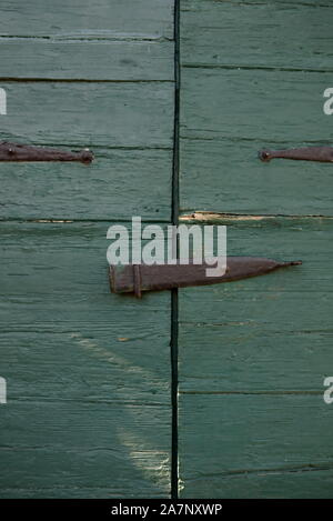 Gros plan de volets en bois anciens, verts et fermés, avec charnières et loquet en métal faits à la main. Banque D'Images