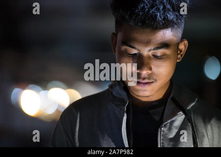 Face à des hommes à l'aide de téléphone dans les rues de la ville la nuit Banque D'Images