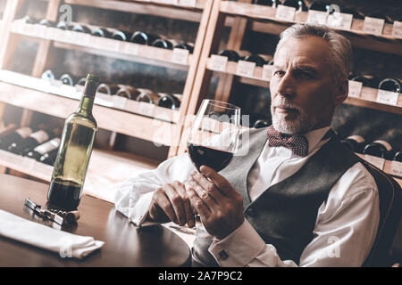Sommelier Concept. Senior avec verre de vin rouge à côté pensive close-up Banque D'Images