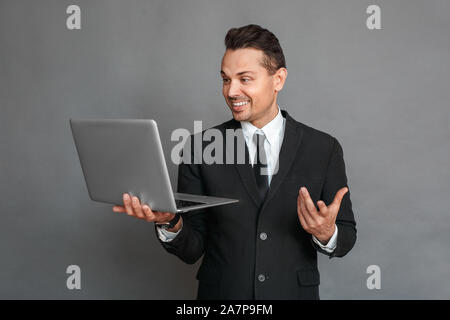 Businessman standing studio isolé sur gray ayant appel vidéo des gestes professionnels Banque D'Images