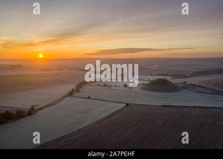 Silbury Hill, Nr Avebury, Wiltshire, Royaume-Uni. 28 octobre 2019. Image d'un drone frosty matin rouge ciel au-dessus de l'homme antique monticule de Silbury Hill. Banque D'Images