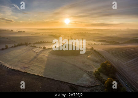 Silbury Hill, Nr Avebury, Wiltshire, Royaume-Uni. 28 octobre 2019. Image d'un drone frosty matin rouge ciel au-dessus de l'homme antique monticule de Silbury Hill. Banque D'Images