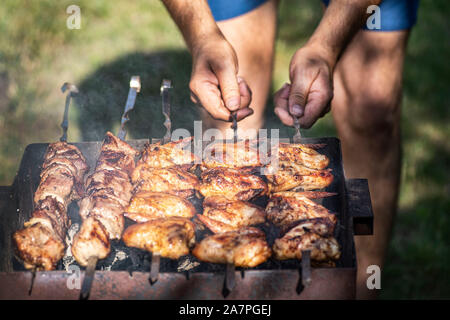 Ailes de poulet en sauce.Un homme tournoie des ailes de poulet sur les brochettes sur Mongal. Kebab de temps. Ailes de poulet frit.barbecue. Banque D'Images