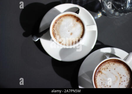 Deux tasses de Cappuccino avec mousse De Lait. Vue en hauteur du café sur le fond sombre. Banque D'Images