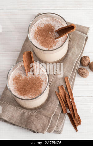 Poule dans des tasses en verre avec une mousse délicate, les épices et un bâton de cannelle Banque D'Images