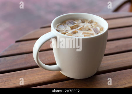 Close up d'iced latte cappuccino thé dans un mug, table en bois historique Banque D'Images