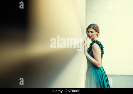 Beautiful woman leaning against wall outdoors looking at camera Banque D'Images