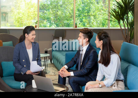 Photographie d'un groupe de trois hommes et femmes d'affaires assis dans un bureau et de parler les uns aux autres tout en souriant Banque D'Images