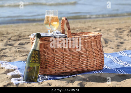 Deux verres de champagne sur un panier de pique-nique contre sable et mer Banque D'Images