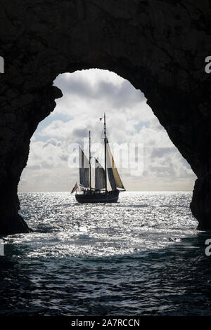 Le Tallship Moonfleet encadrées par l'Arch Rock de Durdle Door, Dorset, UK Banque D'Images