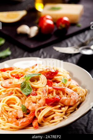 Spaghetti Pâtes aux crevettes, tomates séchées et basilic sur fond noir. Repas sain. Cuisine italienne. Banque D'Images