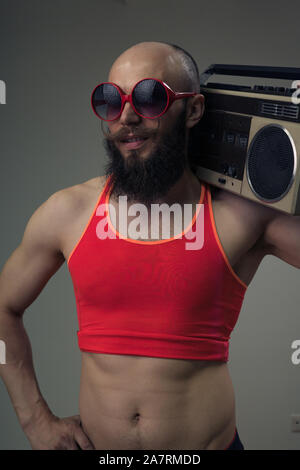 Portrait d'un homme barbu à lunettes noires et d'un fitness t-shirt holding un magnétophone sur son épaule. La préparation pour un retro party Banque D'Images